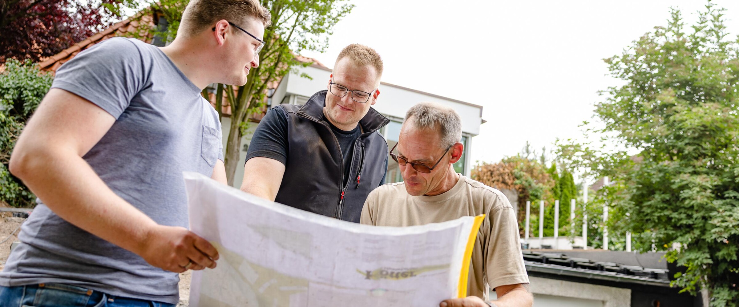 Mitarbeiter von Kötter Garten- und Landschaftsbau besprechen mit Geschäftsführer Lukas Kötter den Plan einer Außenanlage