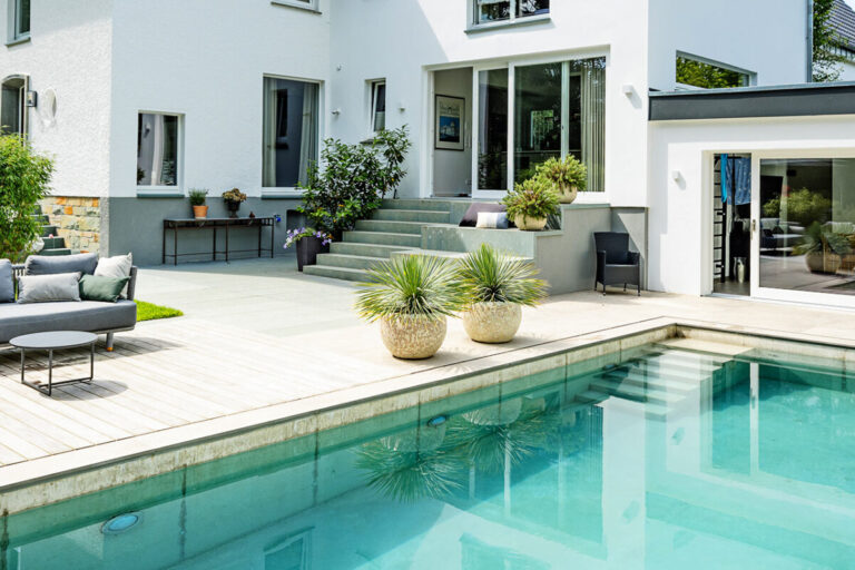 Privatgarten mit Schwimmpool, Holzdeck und Sitzbereich an einem modernen Wohnhaus – Hauptbild für den Bereich Privatgärten von Kötter Garten- und Landschaftsbau