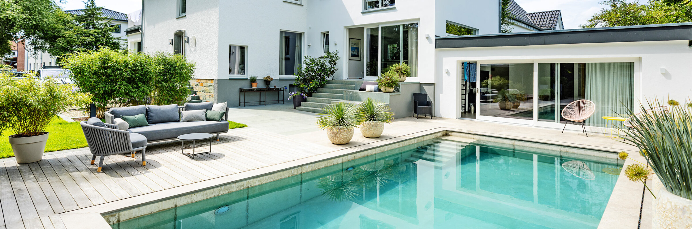 Privatgarten mit Schwimmpool, Holzdeck und Sitzbereich an einem modernen Wohnhaus – Hauptbild für den Bereich Privatgärten von Kötter Garten- und Landschaftsbau