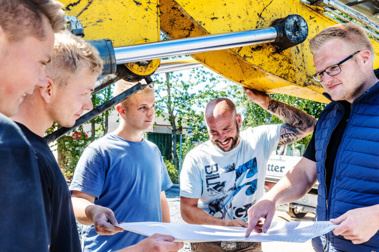 Mitarbeiter von Kötter Garten- und Landschaftsbau besprechen mit Geschäftsführer Lukas Kötter den Plan einer Außenanlage - Stellenangebot: Bauleiter
