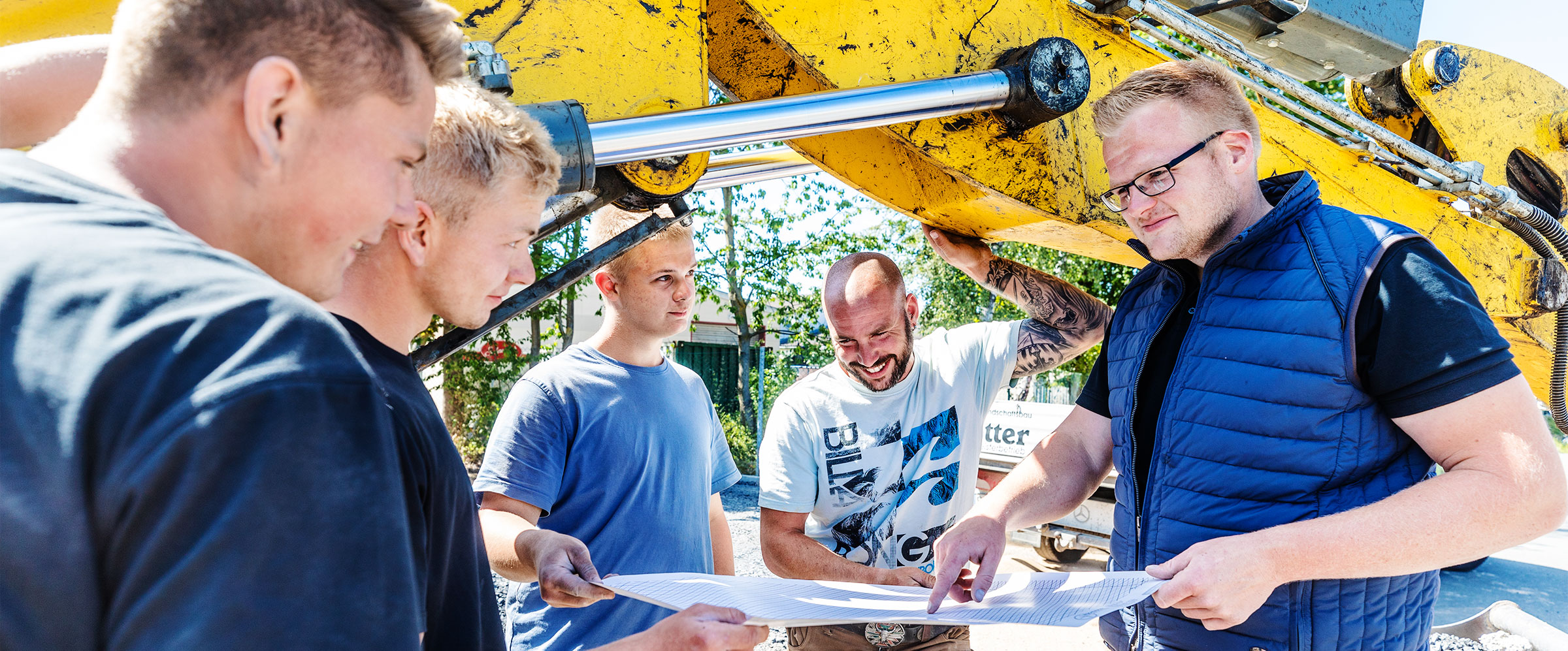 Mitarbeiter von Kötter Garten- und Landschaftsbau besprechen mit Geschäftsführer Lukas Kötter den Plan einer Außenanlage - Stellenangebot: Bauleiter
